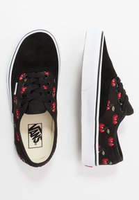 Černé tenisky Vans s výšivkou třešní, zobrazující horní a boční pohled, s černými tkaničkami a bílou gumovou podrážkou.