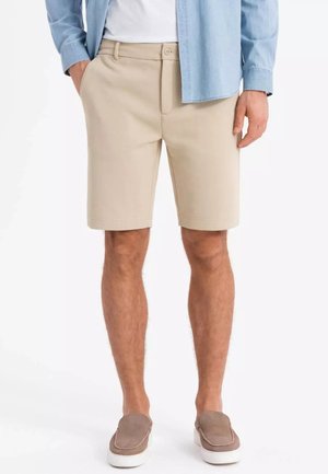 Shorts beiges avec un design à plat à l'avant et des poches latérales. Fabriqués en tissu léger, ils présentent une fermeture par bouton et sont de longueur genou.