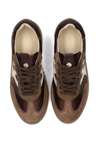 Sneaker marroni con materiali misti: finiture lucide e screpolate, trame contrastanti, design con lacci e un accento bianco.