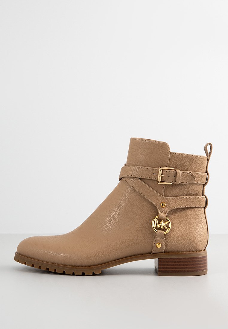 Braune Ankle Boots aus strukturiertem Leder, mit einem Schnallenriemen und einem goldenen Logoakzent, sowie einem braunen Blockabsatz und einer Gummisohle.