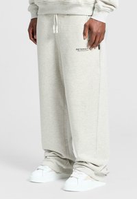 Hellgraue Sweatpants aus weichem Material, mit einem elastischen Bund und seitlichen Taschen, versehen mit dem "RETENRITY"-Logo vorne.