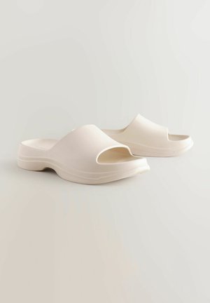 Offene Zehen, reißfeste Sandalen aus mattem, hellem Beigekunststoff. Abgerundetes Design mit einer dicken, gepolsterten Sohle und dezenten Rillen entlang der Kante.