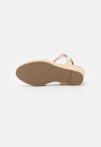 Beige kilehæle sandal med en tekstureret gummisul, der har en vævet jute midtersål og justerbar ankelrem. Glat læderoverdel.