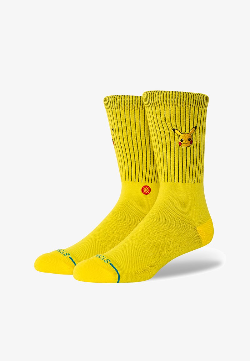 Żółte skarpetki z prążkowanym wzorem i wyszywanym wizerunkiem Pikachu. Zawierają niebieskie i czerwone akcenty na palcach oraz w kostce.