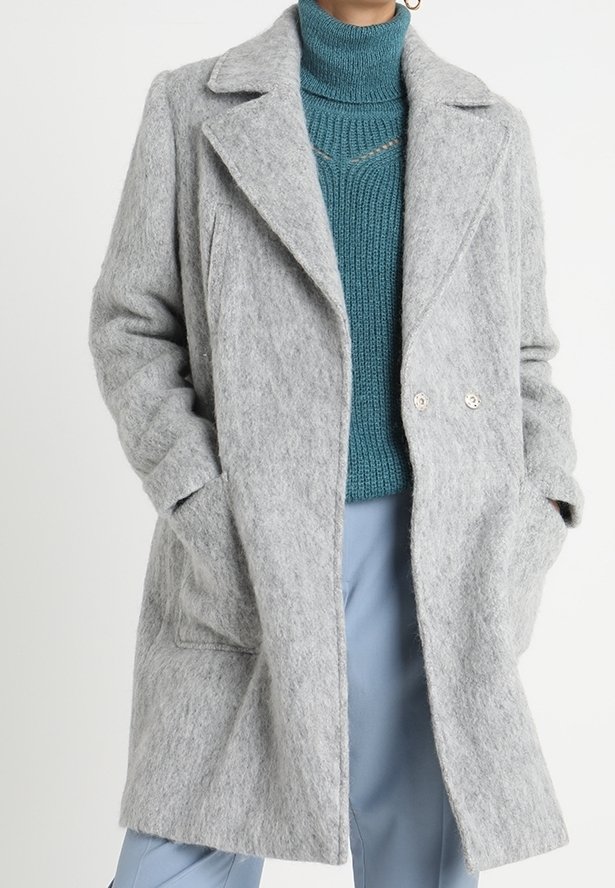 Cappotto in misto lana grigio con rever a punta, chiusura doppiopetto, tasche laterali e una vestibilità rilassata, abbinato a un dolcevita texturizzato color teal.
