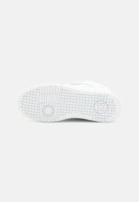 Hvit sneakersåle med teksturert grep mønster, som har en sirkulær aksent og merkevare detalj. Glatt materiale og rund form.