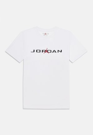 T-shirt blanc à manches courtes avec texte "JORDAN" en noir et logo Jumpman rouge centré sur la poitrine.