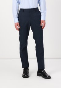 Navy blue trousers with a textured finish, slim fit design, belt loops, and front pockets, paired with black leather shoes.