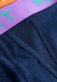 Námořnicky modré boxerky z bavlny s širokým fialovým elastickým pasem se zeleným textem, texturovaným povrchem a zesíleným šitím.