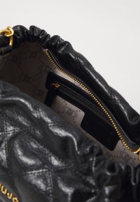 Bolsa de couro preta com parte superior franzida, fecho de ouro e bolso interior com fecho. O interior apresenta um forro estampado.