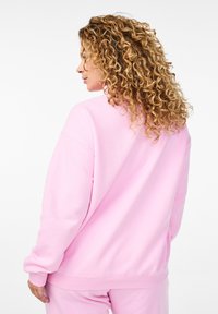 Felpa rosa con una vestibilità comoda e maniche lunghe. Realizzata in un tessuto morbido, presenta polsini a costine e un semplice design della schiena senza cuciture.