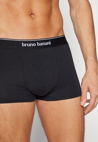 Svarta boxershorts i mjukt tyg, med en kontrasterande elastisk midja med "bruno banani"-logotyp i vitt. Slät textur, åtsittande design.