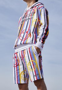 Witte hoodie en short set met een multikleurige gestreepte patroon, uitgerust met lachende gezichten en een tekstlogo nabij de taille. Van katoen materiaal.