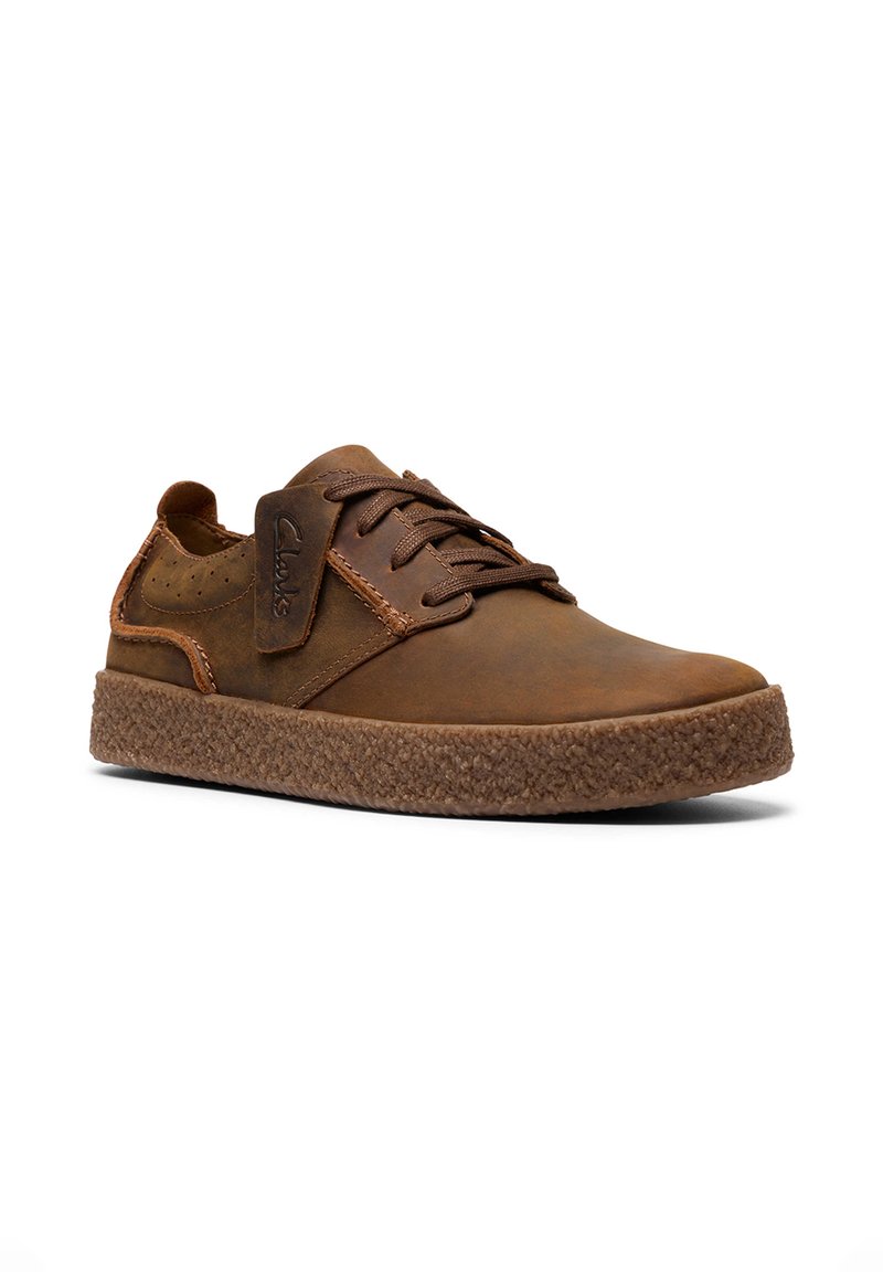 Braune Lederhalbschuh mit runder Spitze, strukturiertem braunem Gummisohle und kontrastierenden Lederakzenten. Mit braunen Schnürsenkeln und durchbrochenem Design.