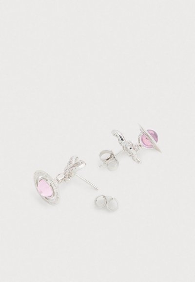 Ασημένια σκουλαρίκια καρφάκια με μοβ ροζ καρδιά πολύτιμη πέτρα, περιβαλλόμενη από κυκλικό πλαίσιο με χαραγμένες λεπτομέρειες. Ομαλή υφή, γυαλισμένη επιφάνεια.