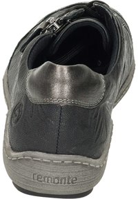 Schwarzer Lederschuh mit strukturiertem Finish, Reißverschluss am Fersenbereich und grauer Gummisohle. Verfügt über eine genähte Kante und Branding.