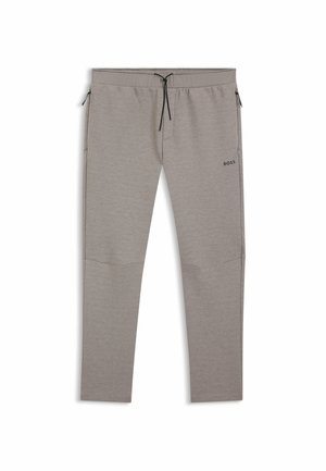 Ljusgrå joggers i mjukt tyg med dragsko i midjan, sidofickor med blixtlås och en liten svart logotyp på vänster lår.