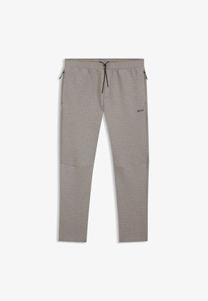 Hellgraue Jogginghosen aus weichem Stoff mit Kordelzugbund, seitlichen Reißverschlusstaschen und einem kleinen schwarzen Logo am linken Oberschenkel.