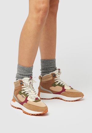 Ben iført grå strikkede sokker og beige, grønne og burgundy højtop-sneakers med hvide snørebånd og tykke hvide såler.