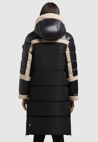 Fekete steppelt kabát bolyhos bézs gallérral, hosszú ujjakkal és mintás anyagrészekkel; cipzáras záródással és ívelt kapucnival.