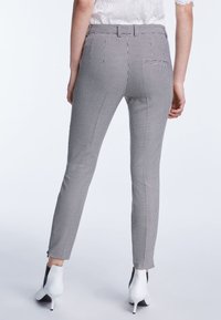 Zwart-witte geblokte broek met een getailleerde pasvorm, platte voorkant en enkelritsen. Gemaakt van een gladde stof, accentueert de slanke silhoutte de vorm van de benen.