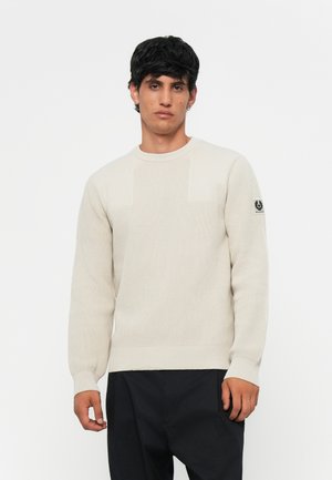 Lys beige strikket sweater med rund halsudskæring, lange ærmer, ribbede manchetter og et logo patch på venstre ærme.