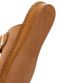 Tan suède sandalen met een zool die is voorzien van een gestructureerde grip, een geribbeld patroon en gladde randen, met een lichte kromming en gouden hardware accent.