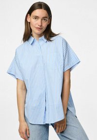 Jasnoniebieska krótko rękawowa koszula zapinana na guziki z pionowymi białymi paskami, wyposażona w kieszeń na piersi i luźny krój z bocznymi rozporkami.