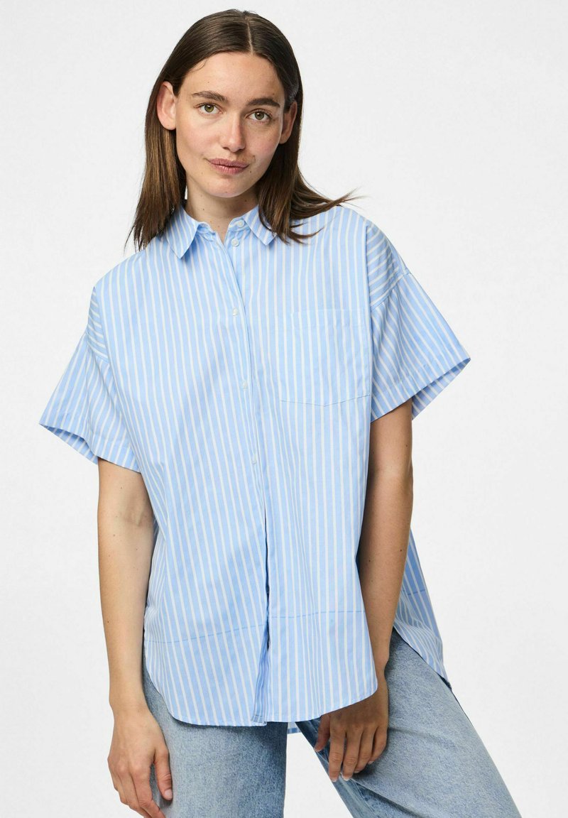 Jasnoniebieska krótko rękawowa koszula zapinana na guziki z pionowymi białymi paskami, wyposażona w kieszeń na piersi i luźny krój z bocznymi rozporkami.