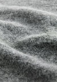 Grått ulltyg med en mjuk, texturerad yta som har fina fibrer och subtila nyansvariationer över det rynkiga materialet.