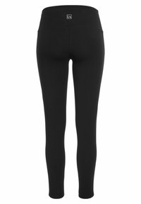 Black leggings made of stretchy fabric, featuring a wide waistband and a small logo detail at the back. Smooth texture and fitted design.