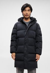 Schwarze Daunenjacke mit Reißverschluss und Druckknopfverschluss, ausgestattet mit einer Kapuze, großen gesteppten Flächen und Seitentaschen. Leichtes Material mit glatter Textur.