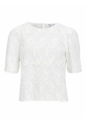 Valge lühikeste varrukatega topp lilleline tikand ja tekstureeritud pind. Omab ümmargust kaelust ja seljaosas võtmeaugu sulgemist.