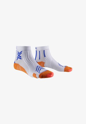 Calcetines deportivos blancos hasta el tobillo con talones y dedos naranjas, patrones geométricos azules y textura acanalada sobre fondo blanco.