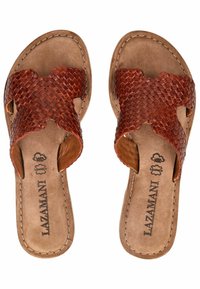 Braune Ledersandalen mit geflochtenem Oberdesign, offenen Seiten und beigen Innensohlen. Auffällige Nähte entlang der Kanten. Markenname sichtbar.