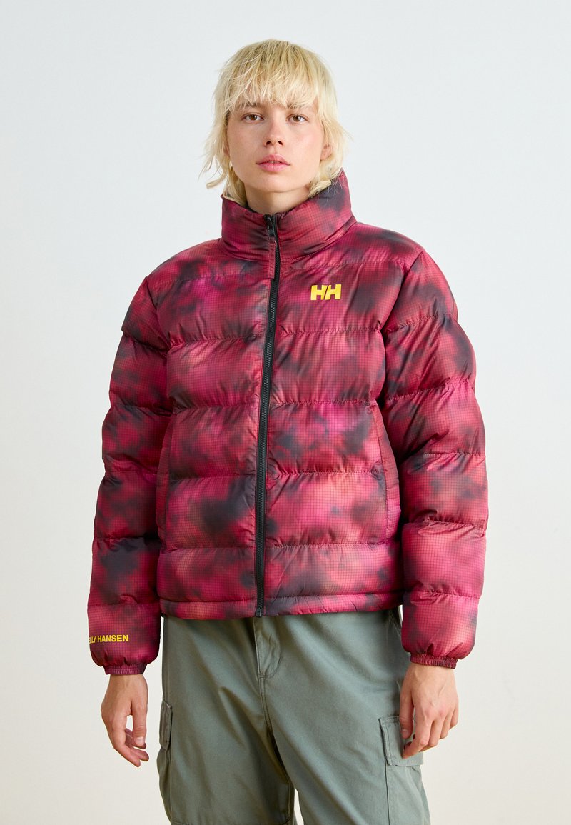 Chaqueta tipo puffer en un patrón degradado rojo y negro, con un alto cuello, cremallera frontal y un logo amarillo en el pecho y la manga. Textura suave y acolchada.