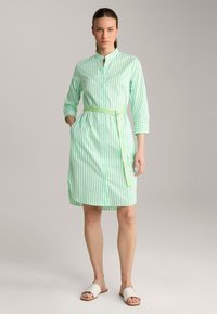 Grün-weiß gestreiftes Hemdkleid mit tailliertem Gürtel, Knopfverschluss und langen Ärmeln. Verfügt über seitliche Taschen und eine glatte Stofftextur.