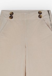 Beige corduroy bukser med lodrette striber, der har to dekorative brune knapper i taljen og lommer på hver side.