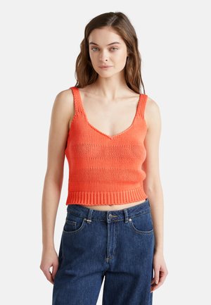 Koralowy, dziany crop top z szerokimi ramiączkami, dekoltem w kształcie litery V oraz ribbowym wykończeniem. Zestawiony z dżinsami o wysokim stanie. Płaski, teksturowany materiał.