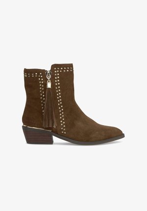 Braune Suede-Ankle-Boots mit spitzer Zehenpartie, Reißverschluss, Nietenakzenten an den Seiten und einem Quasten-Detail in der Nähe des Reißverschlusses. Niedriger Blockabsatz.