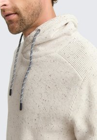 Beige Kapuzenpullover aus strukturiertem Strick, mit gesprenkelten Details und dunkelgrauen Kordeln mit schwarzen Enden.