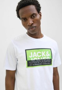 Weißes Baumwoll-T-Shirt mit einem schwarzen und grünen rechteckigen Grafikdesign und dem Text "JACK & JONES", kurzen Ärmeln und Rundhalsausschnitt.