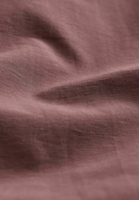 Tissu marron doux avec de fines stries horizontales et des plis doux créant une surface texturée.