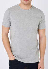 Graues kurzärmliges T-Shirt aus weichem Material. Mit Rundhalsausschnitt und slim fit. Getragen mit dunklen blauen Jeans.