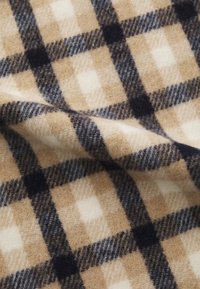 Tejido de cuadros beige y crema con líneas en azul oscuro y negro, textura suave y aspecto acogedor, con grandes patrones cuadrados.