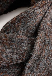 Getextureerde gebreide sjaal met een mix van donkerbruine, grijze en roestrode vezels. De stof lijkt zacht met een los geweven patroon.