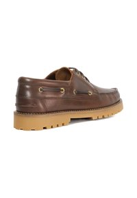 Brown leather shoe with a rounded toe, tan rubber sole, and metal eyelets. Features stitching and a textured finish on the upper.