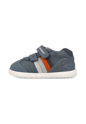 Pequeña zapatilla deportiva gris oscuro con suela blanca, rayas laterales grises y naranjas, y dos tiras de velcro para abrochar.