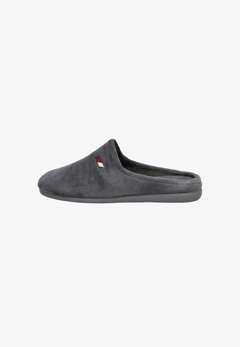 Zapatilla de tela suave y gris, tipo pantufla, con punta cerrada y parte trasera abierta, y un pequeño detalle bordado en rojo, blanco y negro en el lateral.