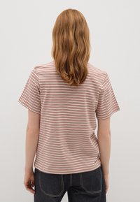 Camiseta de manga corta a rayas en crema claro con rayas rojas horizontales; tejido suave, corte relajado, bajo redondeado, con un detalle mínimo.